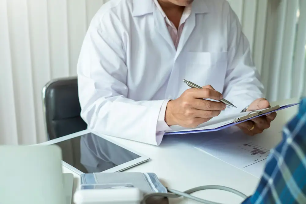 Vascular surgeon reviewing practice management and billing documents at a clinical desk